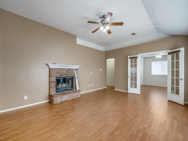 unfurnished living room featuring light wood-type flooring, ceiling fan, french doors, and a brick fireplace