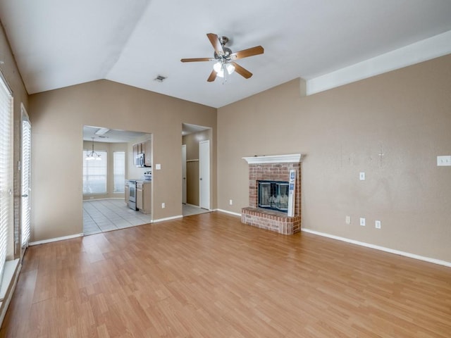 unfurnished living room featuring vaulted ceiling, ceiling fan with notable chandelier, light hardwood / wood-style flooring, and a fireplace