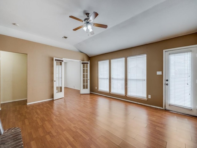 unfurnished living room with light hardwood / wood-style floors, vaulted ceiling, ceiling fan, and french doors