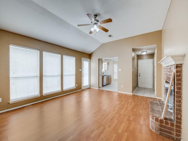 unfurnished living room featuring ceiling fan, a fireplace, light hardwood / wood-style flooring, and vaulted ceiling