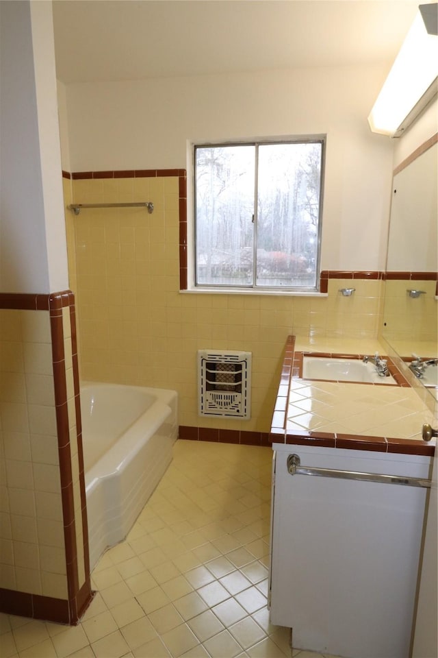 bathroom featuring a bathing tub, heating unit, tile walls, vanity, and tile patterned floors