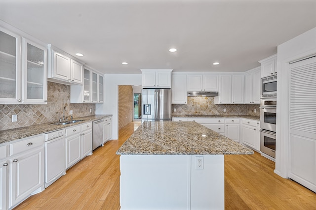 kitchen featuring light stone counters, a center island, white cabinetry, and appliances with stainless steel finishes