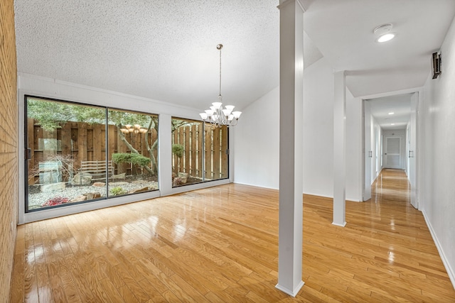 interior space featuring a textured ceiling, hardwood / wood-style flooring, and a chandelier