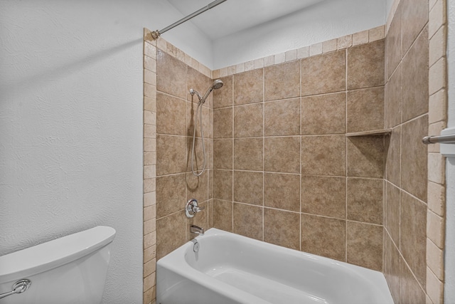 bathroom with tiled shower / bath combo and toilet