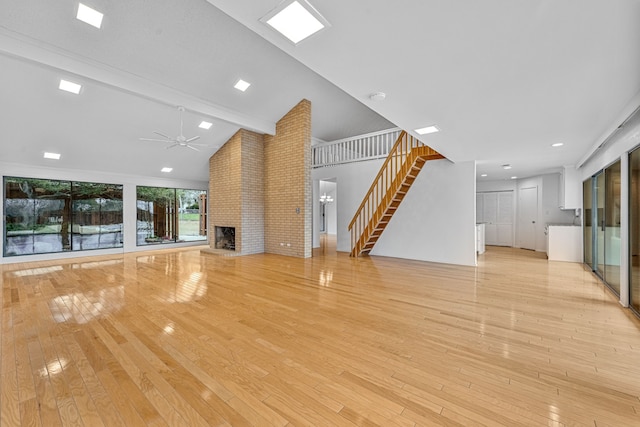 unfurnished living room featuring a brick fireplace, light hardwood / wood-style floors, ceiling fan, and vaulted ceiling with beams