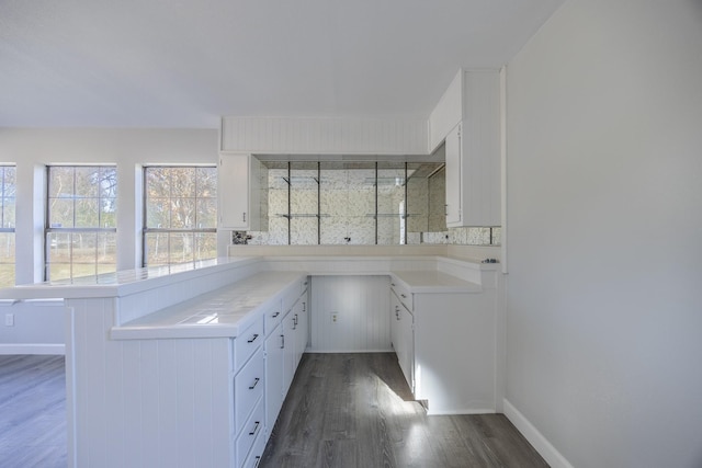 kitchen featuring kitchen peninsula, backsplash, white cabinetry, and dark hardwood / wood-style floors