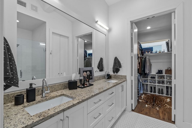 bathroom featuring tile patterned flooring, a shower with shower door, and vanity