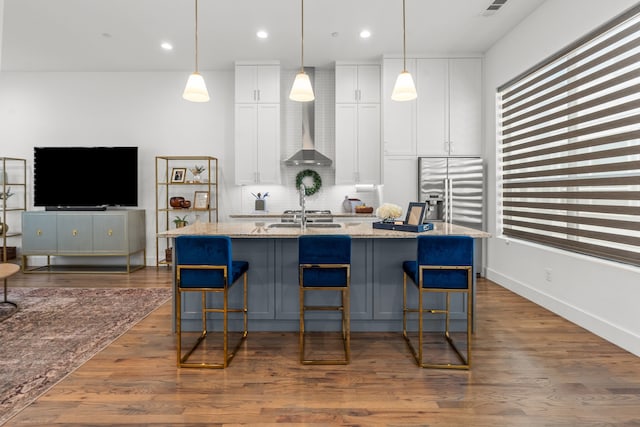 kitchen with light stone counters, white cabinets, a kitchen island with sink, and tasteful backsplash