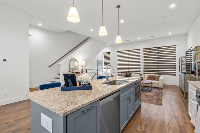 kitchen with appliances with stainless steel finishes, gray cabinetry, sink, decorative light fixtures, and an island with sink