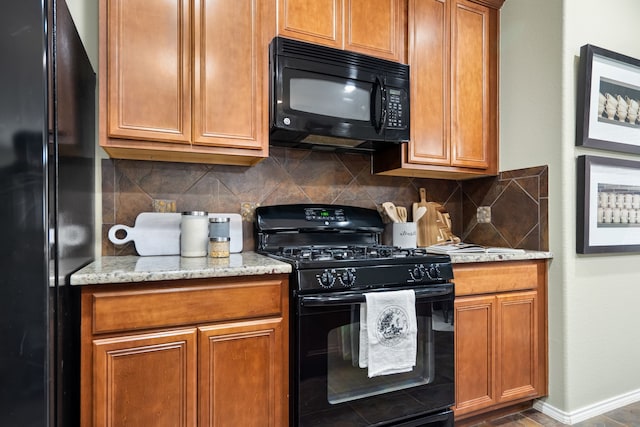 kitchen featuring black appliances, decorative backsplash, and light stone countertops