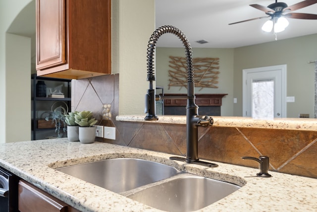 kitchen with sink, decorative backsplash, light stone countertops, and ceiling fan