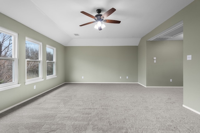 empty room with ceiling fan, a wealth of natural light, light carpet, and vaulted ceiling