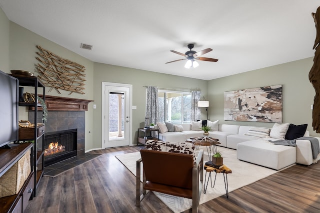 living room with ceiling fan, dark wood-type flooring, and a tile fireplace