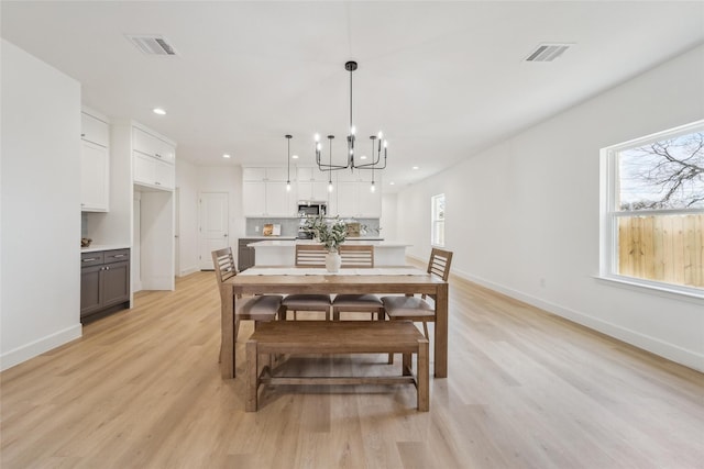 dining room with light wood-style flooring, visible vents, and baseboards