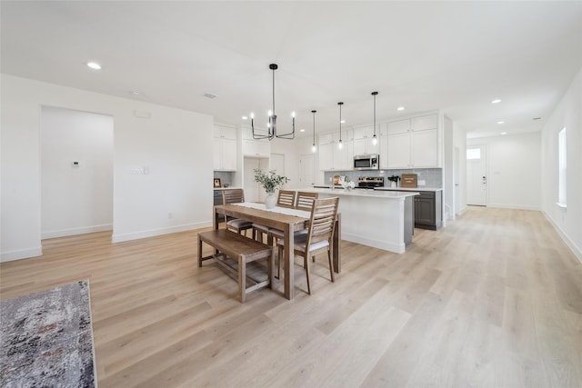 dining area with baseboards, an inviting chandelier, light wood-style flooring, and recessed lighting