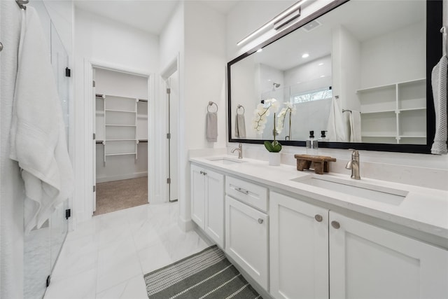 bathroom featuring a stall shower, a spacious closet, visible vents, and a sink