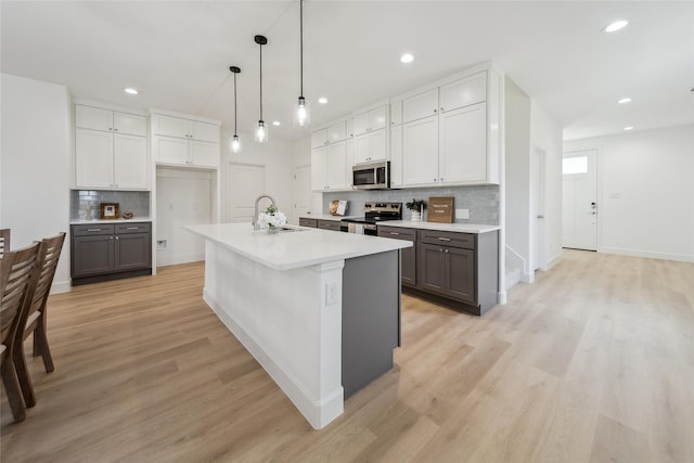 kitchen with stainless steel appliances, light wood-style floors, gray cabinets, and a sink