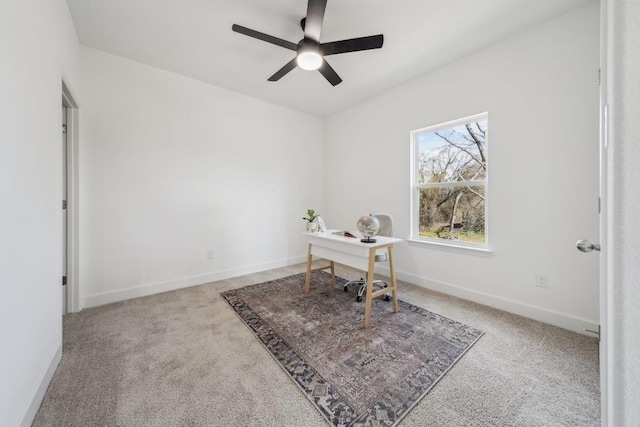 carpeted home office with ceiling fan and baseboards