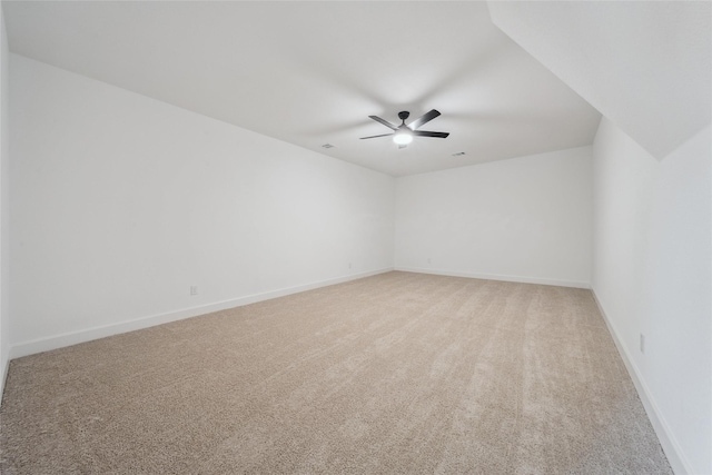 empty room featuring a ceiling fan, light colored carpet, and baseboards