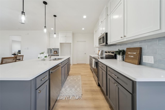 kitchen featuring decorative backsplash, appliances with stainless steel finishes, light wood-type flooring, white cabinetry, and a sink