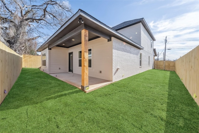 back of property featuring a patio area, brick siding, a lawn, and a fenced backyard