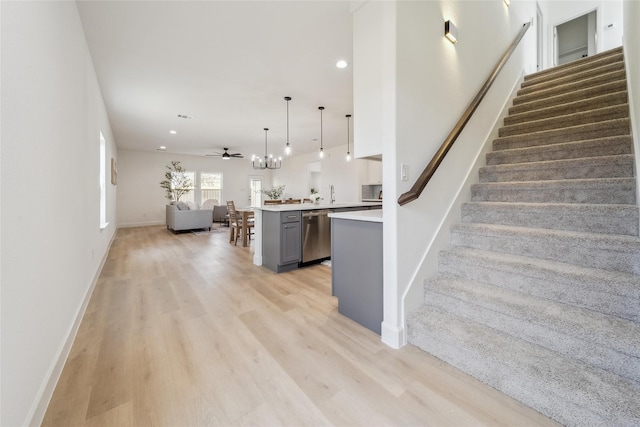 kitchen featuring gray cabinetry, open floor plan, light countertops, light wood-type flooring, and dishwasher