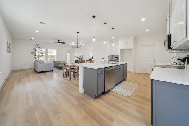 kitchen with stainless steel appliances, light countertops, gray cabinetry, open floor plan, and a sink