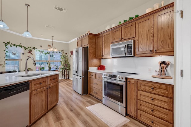 kitchen with appliances with stainless steel finishes, sink, hanging light fixtures, light wood-type flooring, and crown molding