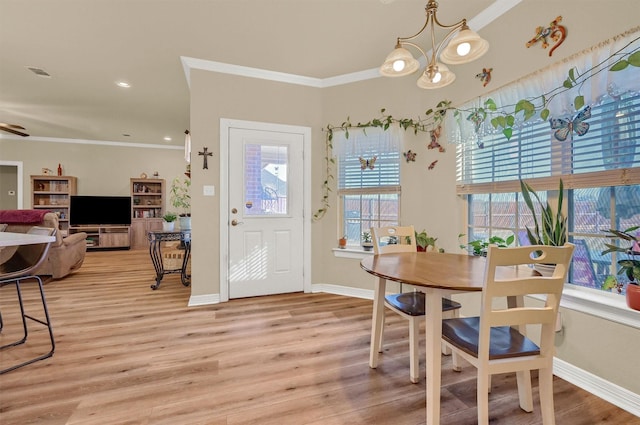 dining space featuring light hardwood / wood-style floors, crown molding, and a chandelier