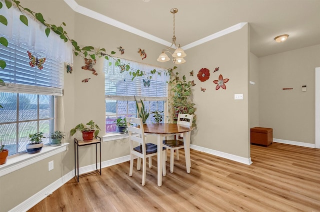 dining space with light wood-type flooring, ornamental molding, and a notable chandelier