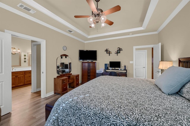 bedroom featuring crown molding, ceiling fan, a raised ceiling, hardwood / wood-style flooring, and ensuite bath