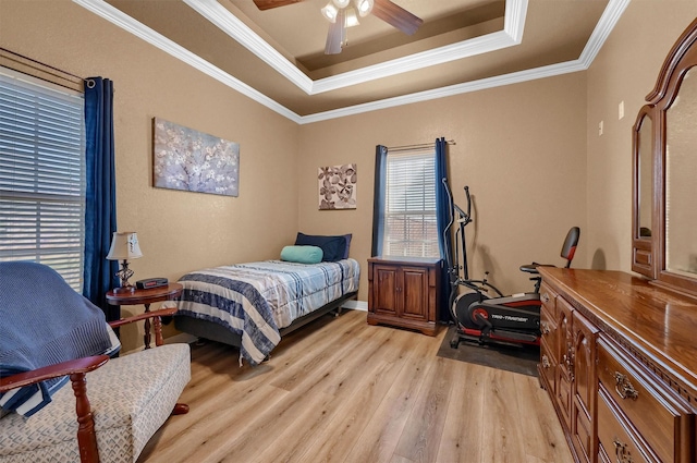 bedroom featuring ceiling fan, light hardwood / wood-style floors, a tray ceiling, and ornamental molding