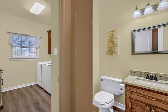 bathroom with hardwood / wood-style flooring, toilet, vanity, and washing machine and clothes dryer