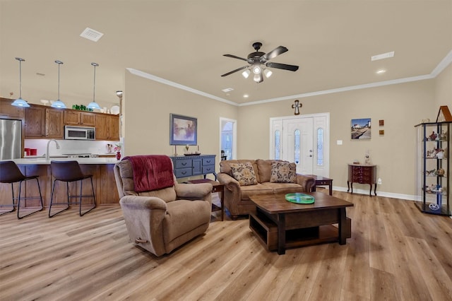 living room featuring light wood-type flooring, ceiling fan, crown molding, and sink