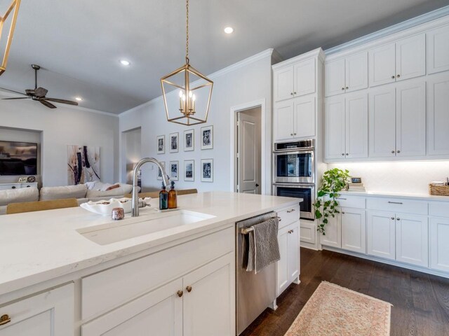 kitchen with dark hardwood / wood-style floors, decorative light fixtures, white cabinetry, sink, and stainless steel appliances