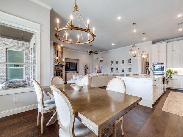 dining room featuring dark hardwood / wood-style floors, a fireplace, ornamental molding, brick wall, and ceiling fan with notable chandelier