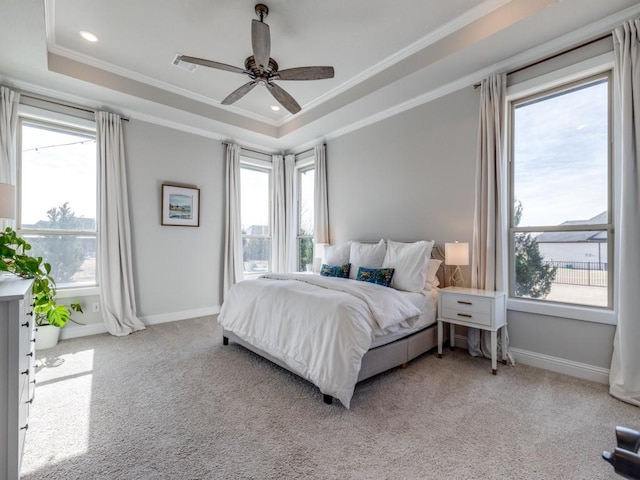 carpeted bedroom with a raised ceiling, crown molding, and ceiling fan