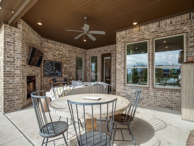 view of patio with an outdoor living space with a fireplace and ceiling fan