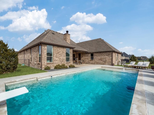 view of swimming pool with a diving board and a patio