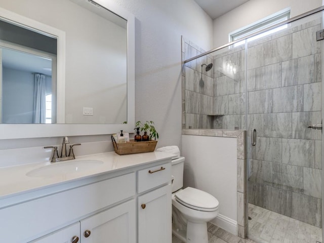 bathroom featuring vanity, a shower with door, and toilet