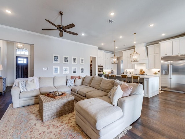 living room with ceiling fan with notable chandelier, wood-type flooring, and ornamental molding