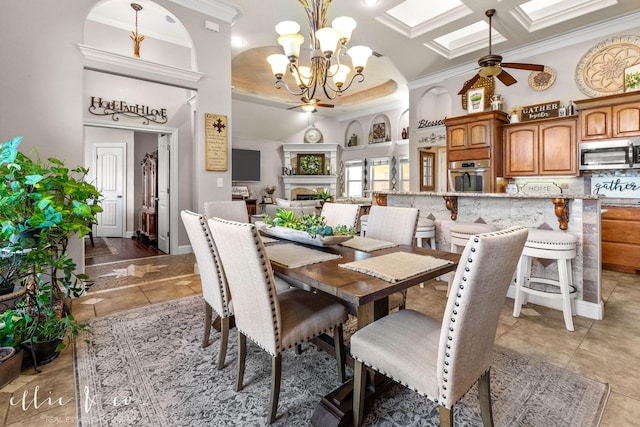 dining room featuring ceiling fan with notable chandelier, tile patterned floors, crown molding, and coffered ceiling