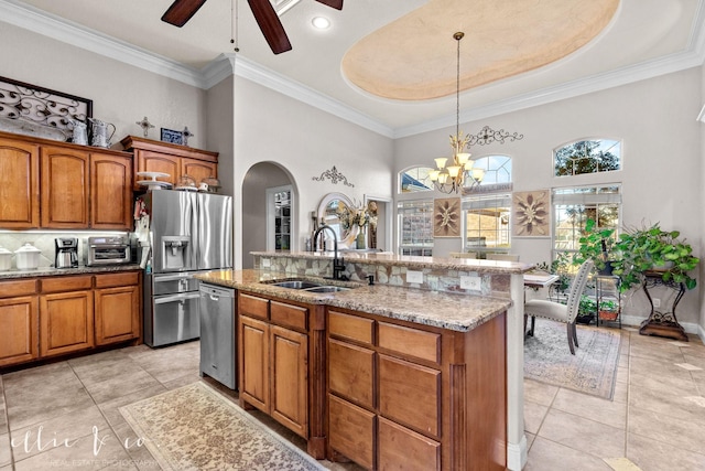 kitchen featuring hanging light fixtures, appliances with stainless steel finishes, sink, a tray ceiling, and an island with sink