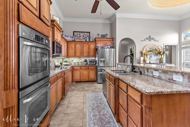 kitchen featuring sink, light tile patterned floors, a kitchen island with sink, ornamental molding, and stainless steel appliances