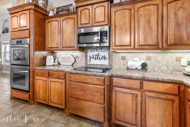 kitchen with decorative backsplash, light stone countertops, stainless steel appliances, and light tile patterned flooring