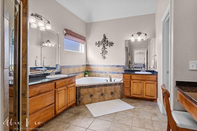 bathroom with tiled bath, vanity, and tile patterned flooring