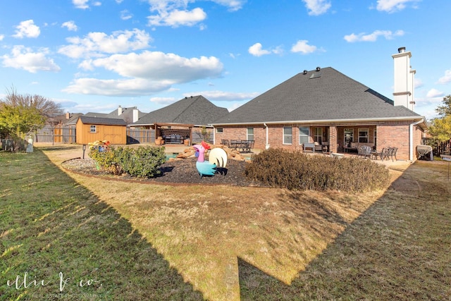 back of property with a patio area, a yard, and a storage unit