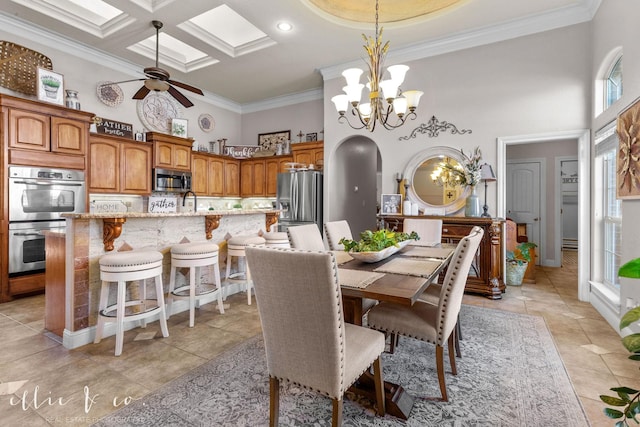 tiled dining room with ceiling fan with notable chandelier, a high ceiling, ornamental molding, and coffered ceiling