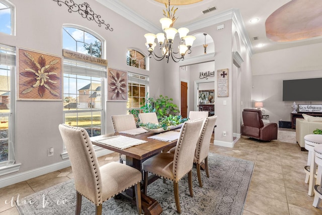 tiled dining area featuring a high ceiling, crown molding, a raised ceiling, and a notable chandelier