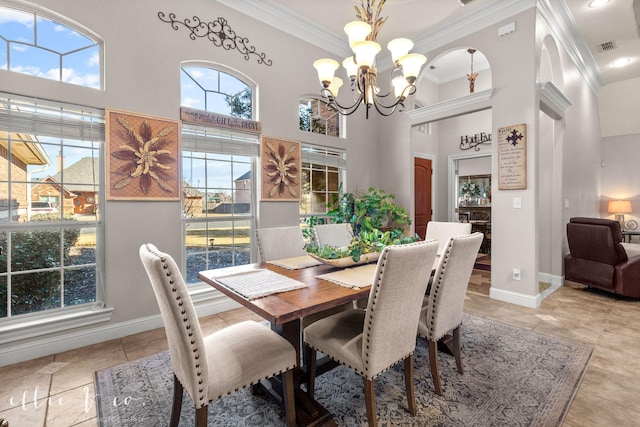 dining area featuring ornamental molding, a towering ceiling, and an inviting chandelier